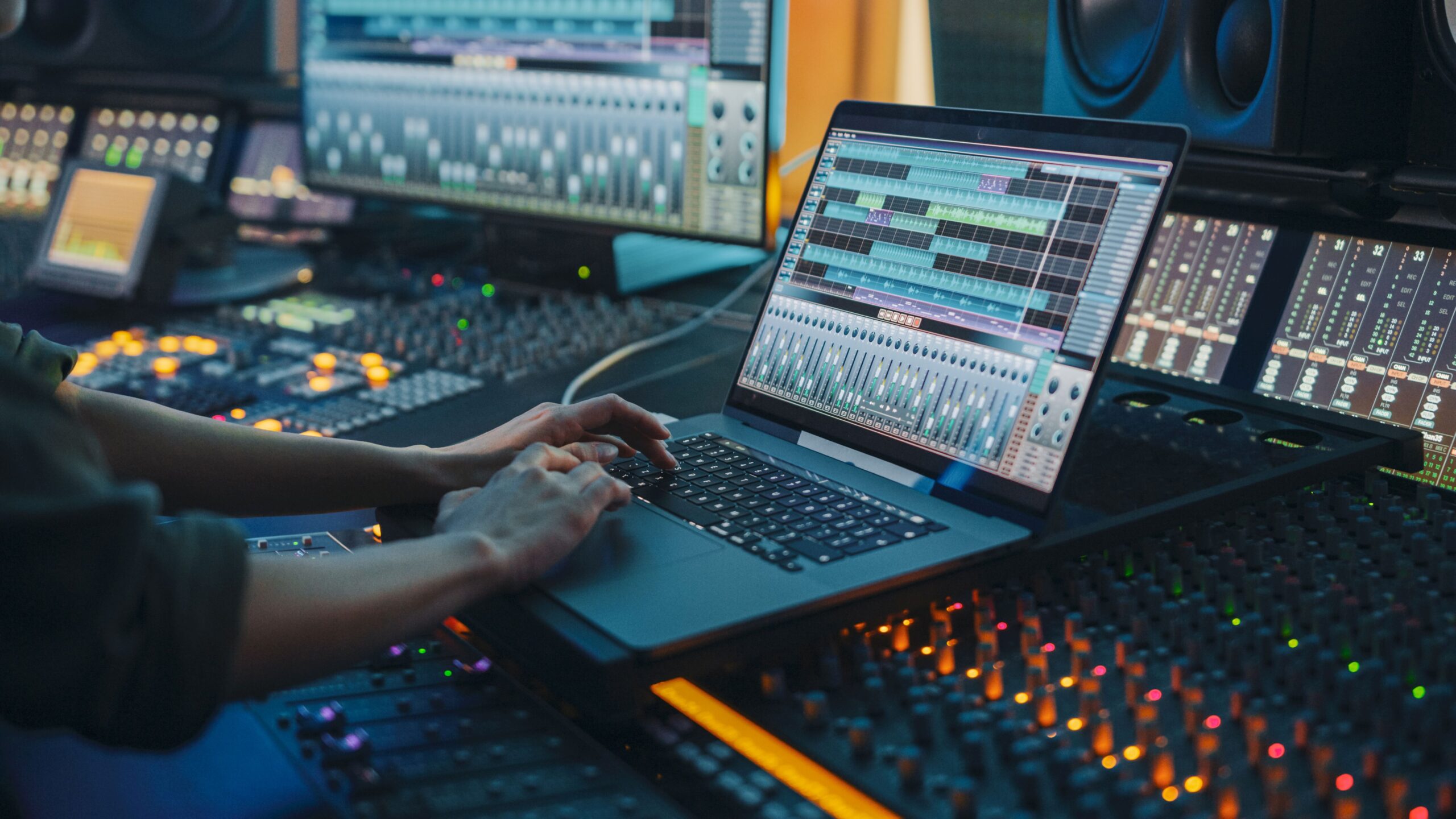 Person arbeitet an einem Laptop mit Audiobearbeitungssoftware in einem Tonstudio