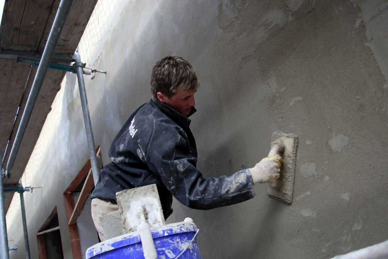 Handwerker verputzt alte Fassade – handwerklicher Teil einer Altbausanierung Berlin
