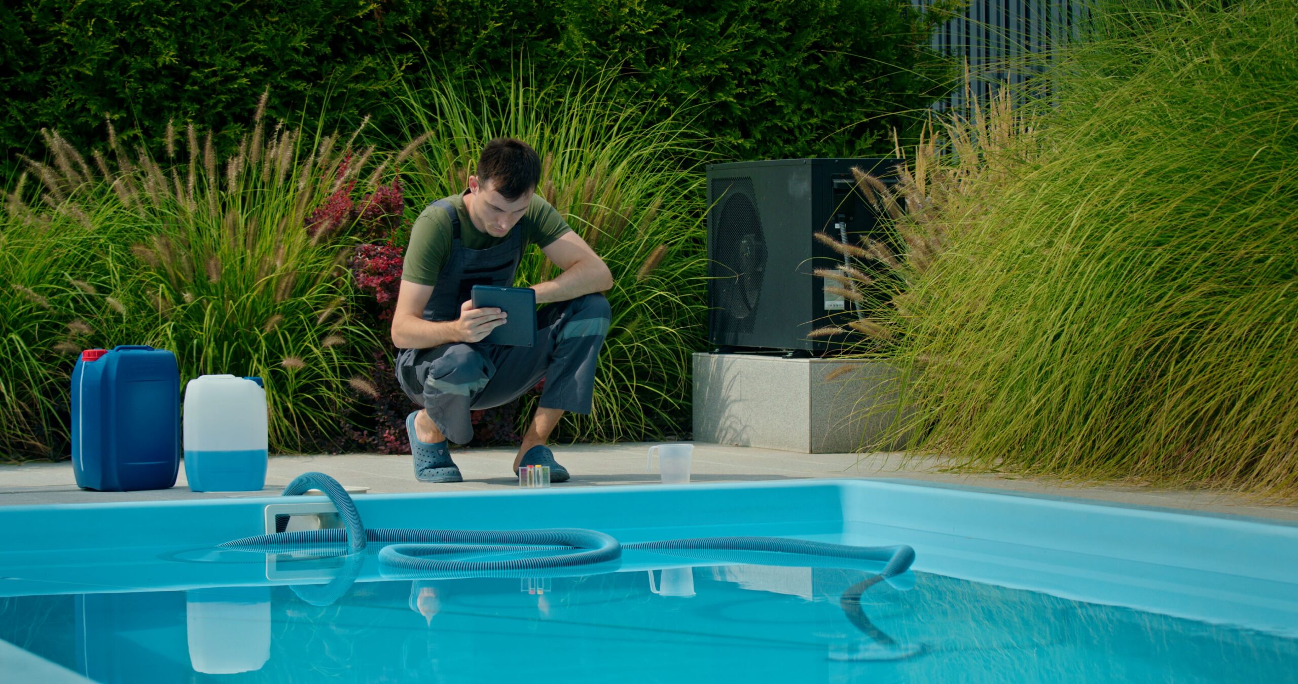 Mann überprüft GFK Pool Steuerung und Technik per Tablet im Garten