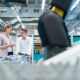 Zwei Fachkraefte in heller Kleidung im Gespraech neben einer Produktionslinie in einer modernen Industriehalle