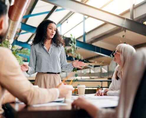 Eine Frau erklärt im Teammeeting strategische Aspekte von einkauf verhandlungsstrategien und Gesprächsführung