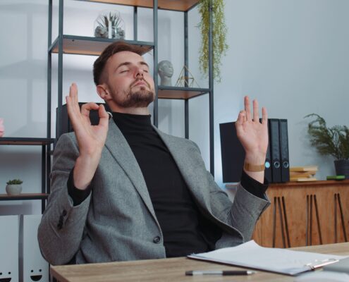 Mann meditiert entspannt im Büro am Schreibtisch | Enthärtungsanlage