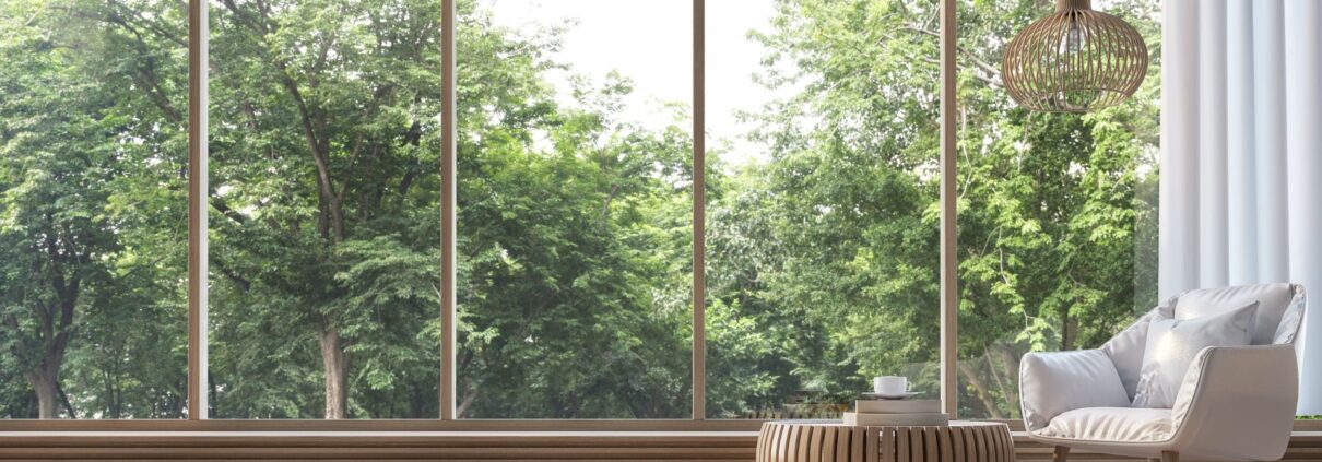 Modernes Wohnzimmer mit großen Panoramafenstern in Wuppertal, handwerklich gefertigte Rahmen öffnen den Blick ins Grüne.